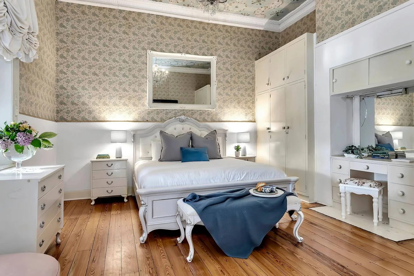 Un dormitorio con una cama, mesitas de noche y papel pintado estampado.
