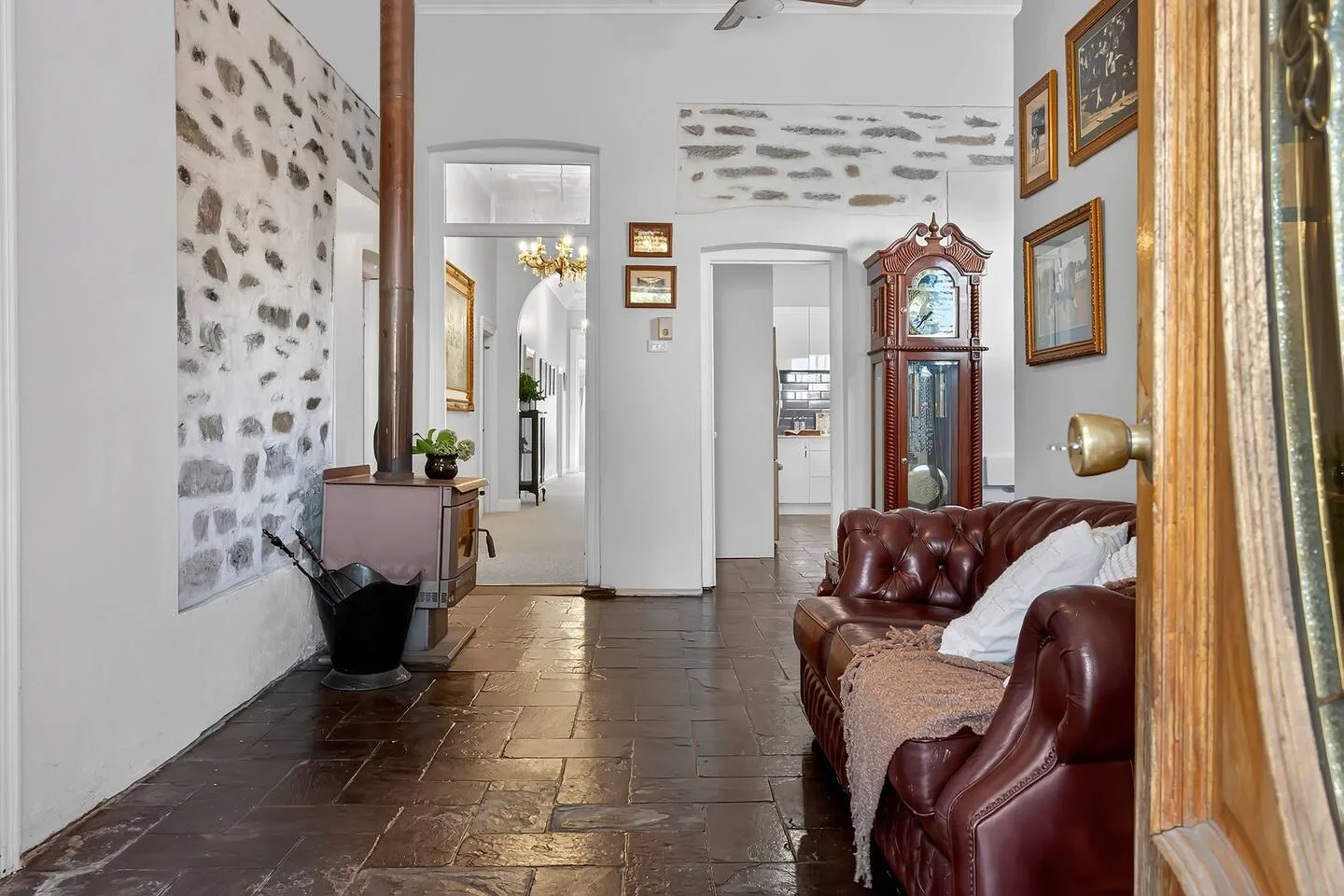 Una sala de estar con asientos de cuero, una estufa de leña y un reloj alto.