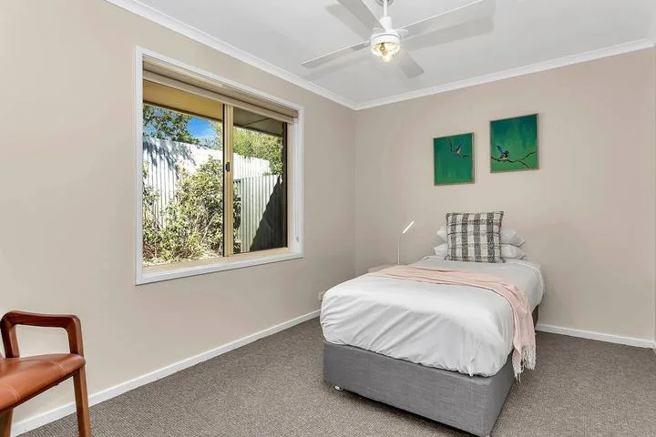 Un dormitorio con una cama, una ventana y dos cuadros en la pared.