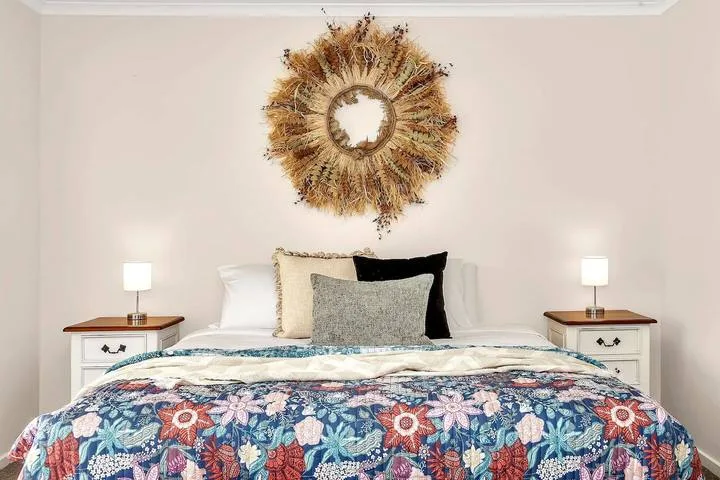 Un dormitorio con una cama, ropa de cama estampada y mesas de noche a juego.