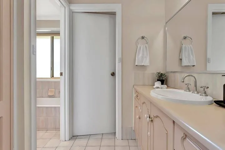 Un tocador de baño con lavabo y espejo junto a una puerta.