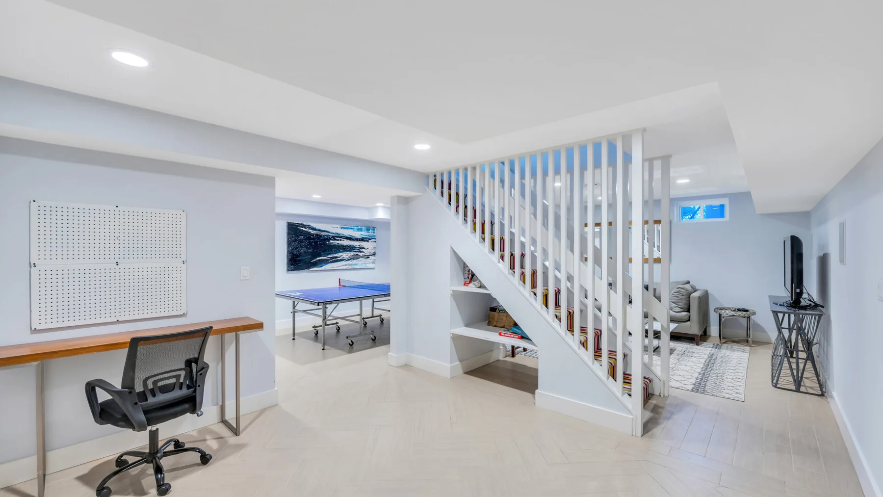 Una luminosa zona recreativa interior con escritorio, asientos y una escalera.