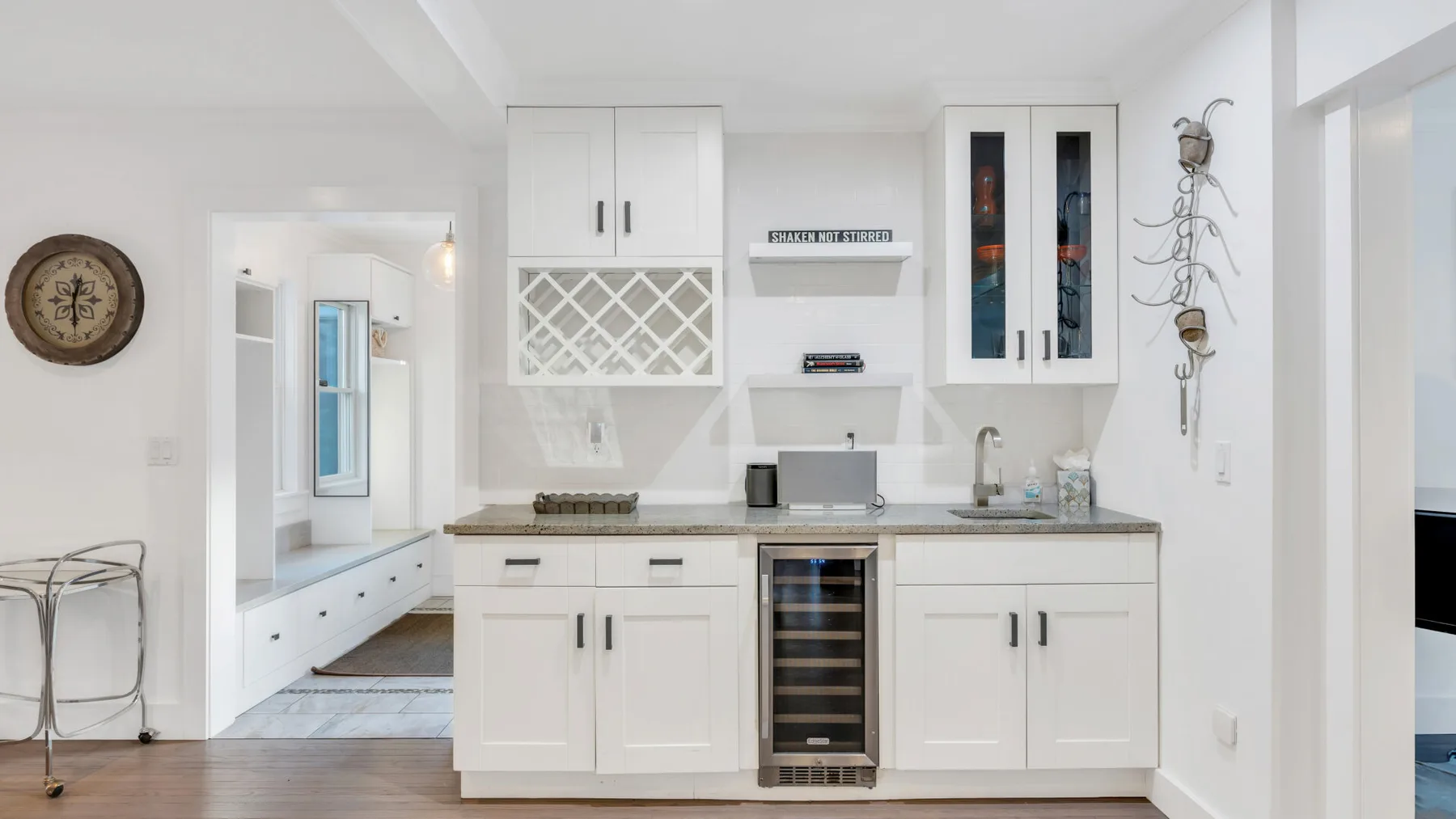 Una cocina blanca y luminosa con gabinetes empotrados y una vinoteca con puerta de vidrio.