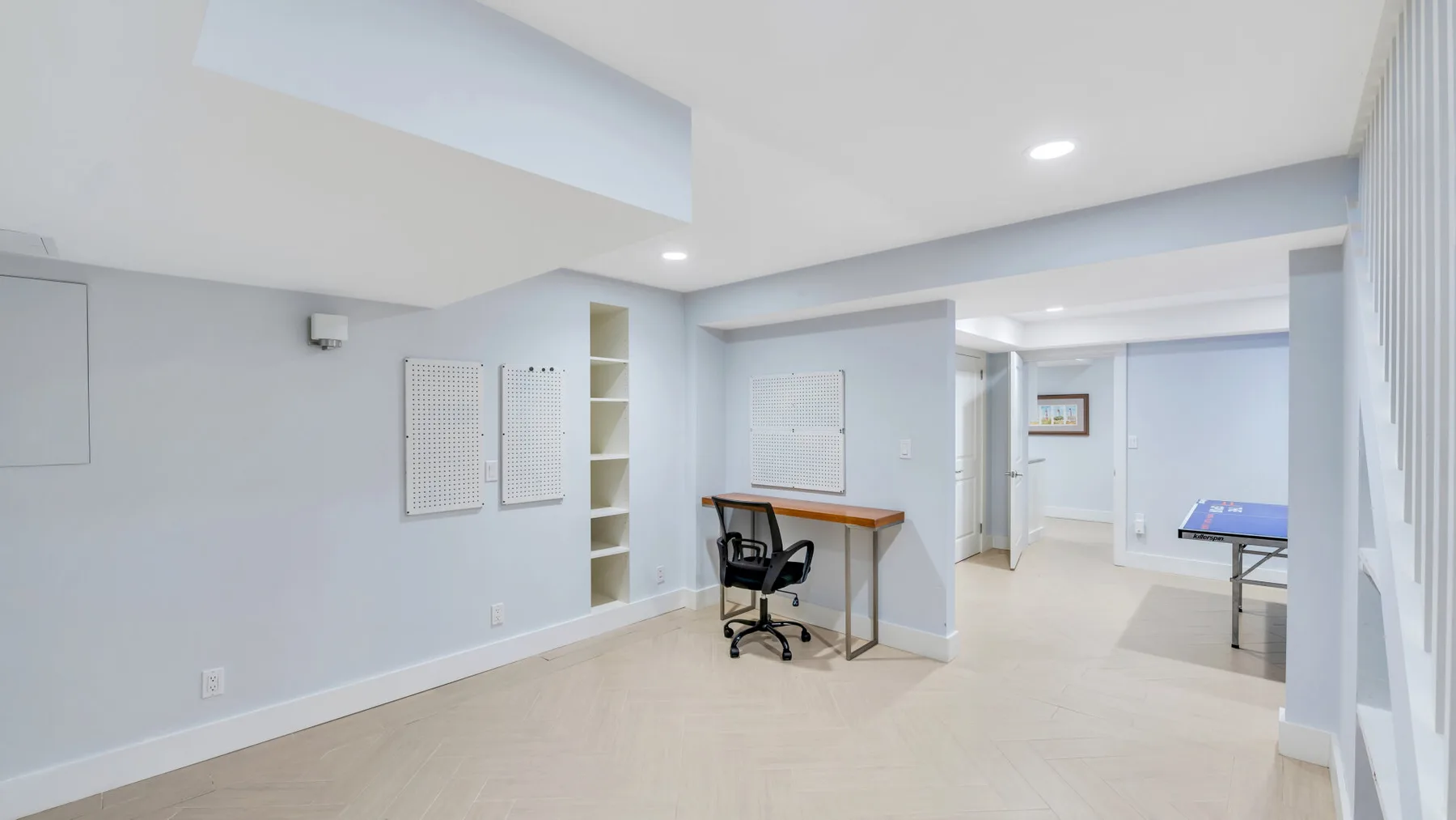 Un espacio de trabajo luminoso con escritorio y silla se abre a un pasillo.