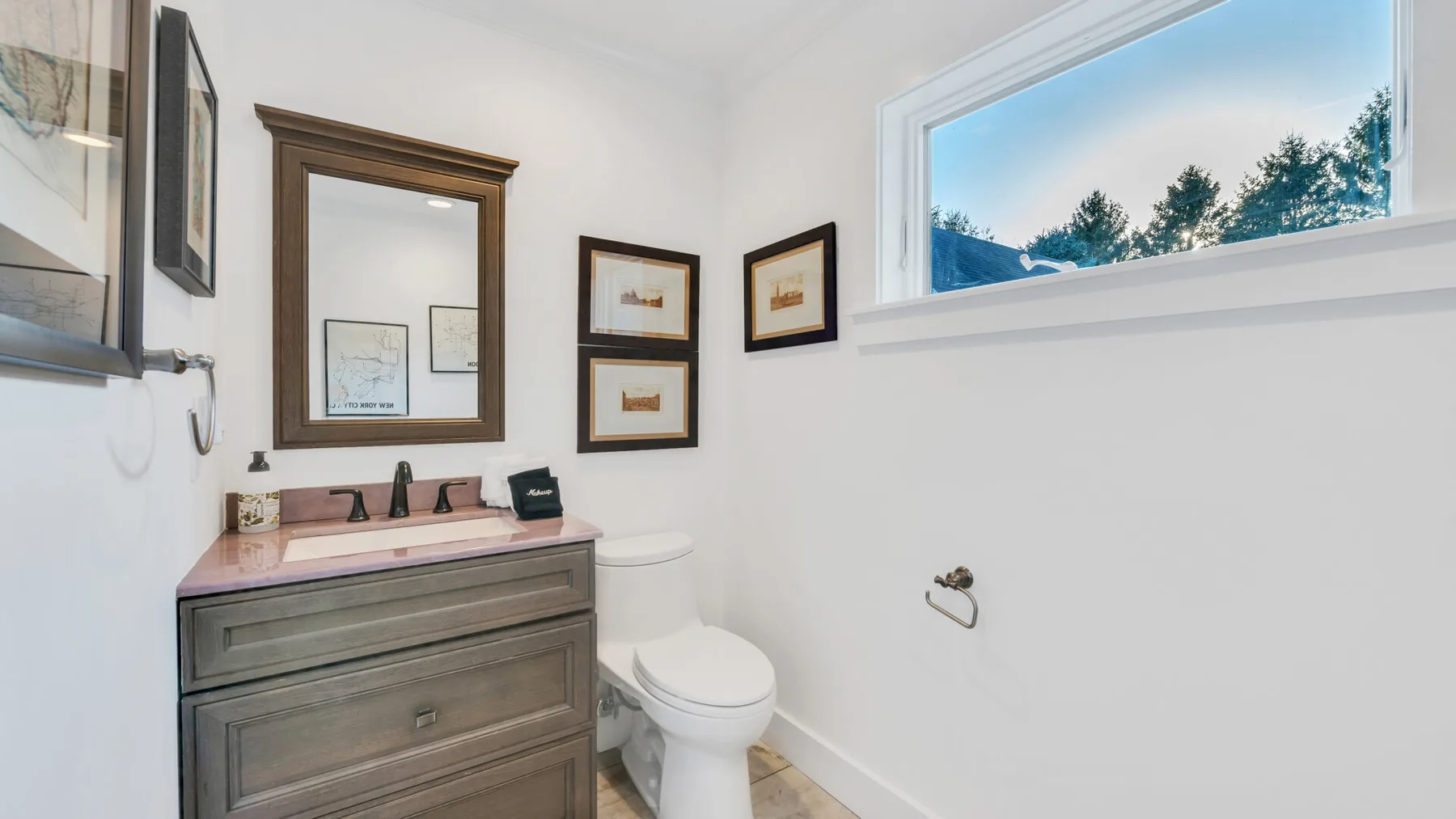 Un baño con lavabo, espejo, inodoro y una ventana amplia.