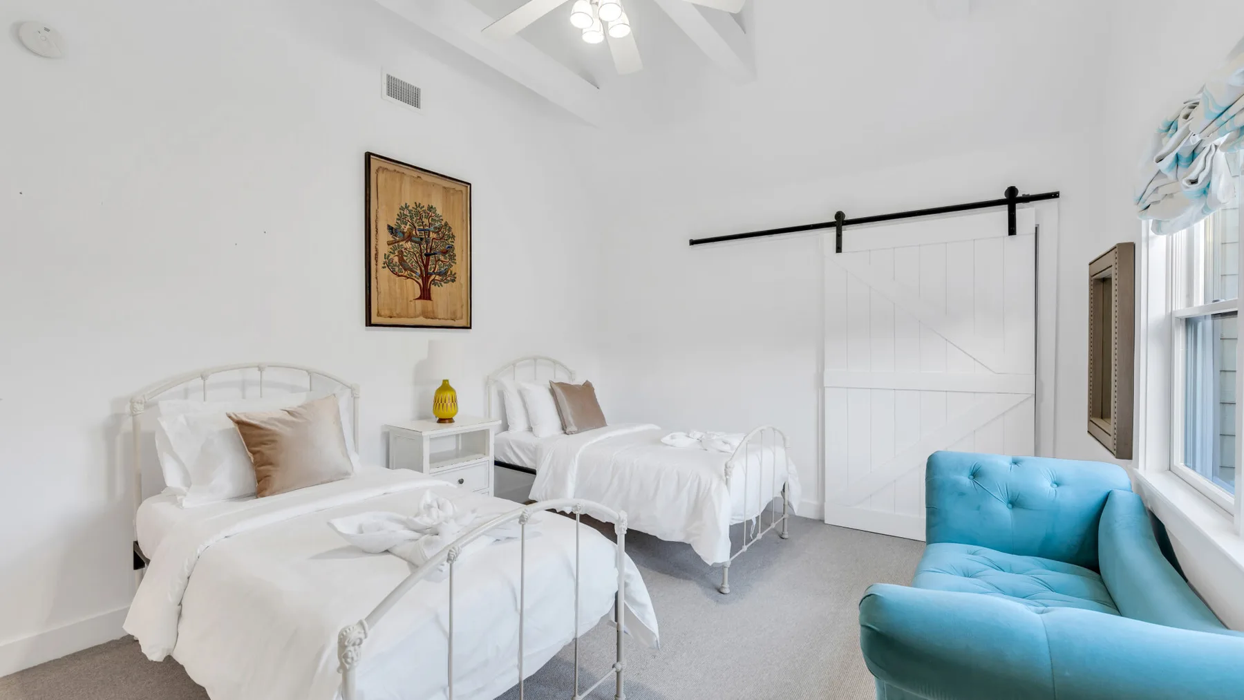 Un dormitorio luminoso con dos camas y una zona de asientos azul.