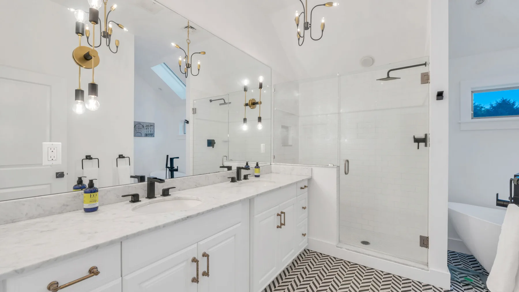 Un baño luminoso con un tocador largo, espejo y ducha de vidrio.