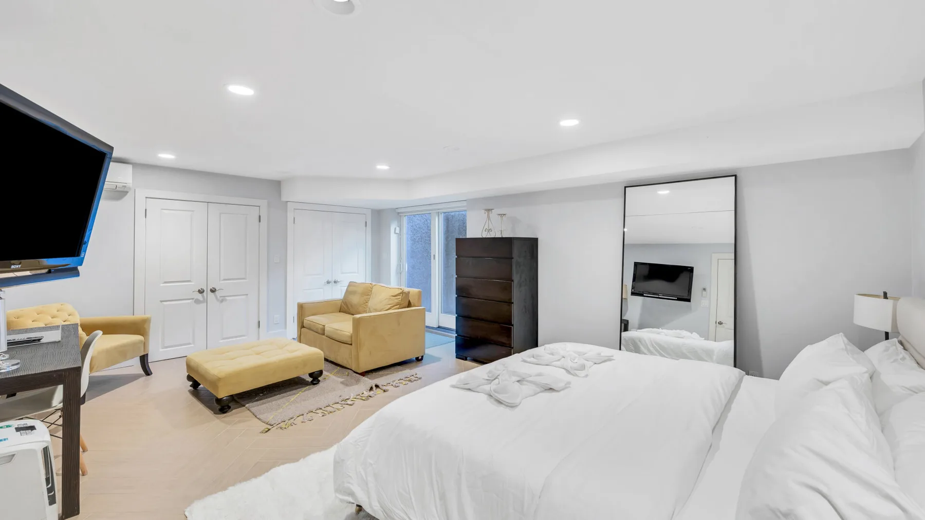 Un dormitorio luminoso con una cama grande, una zona de estar y un televisor.