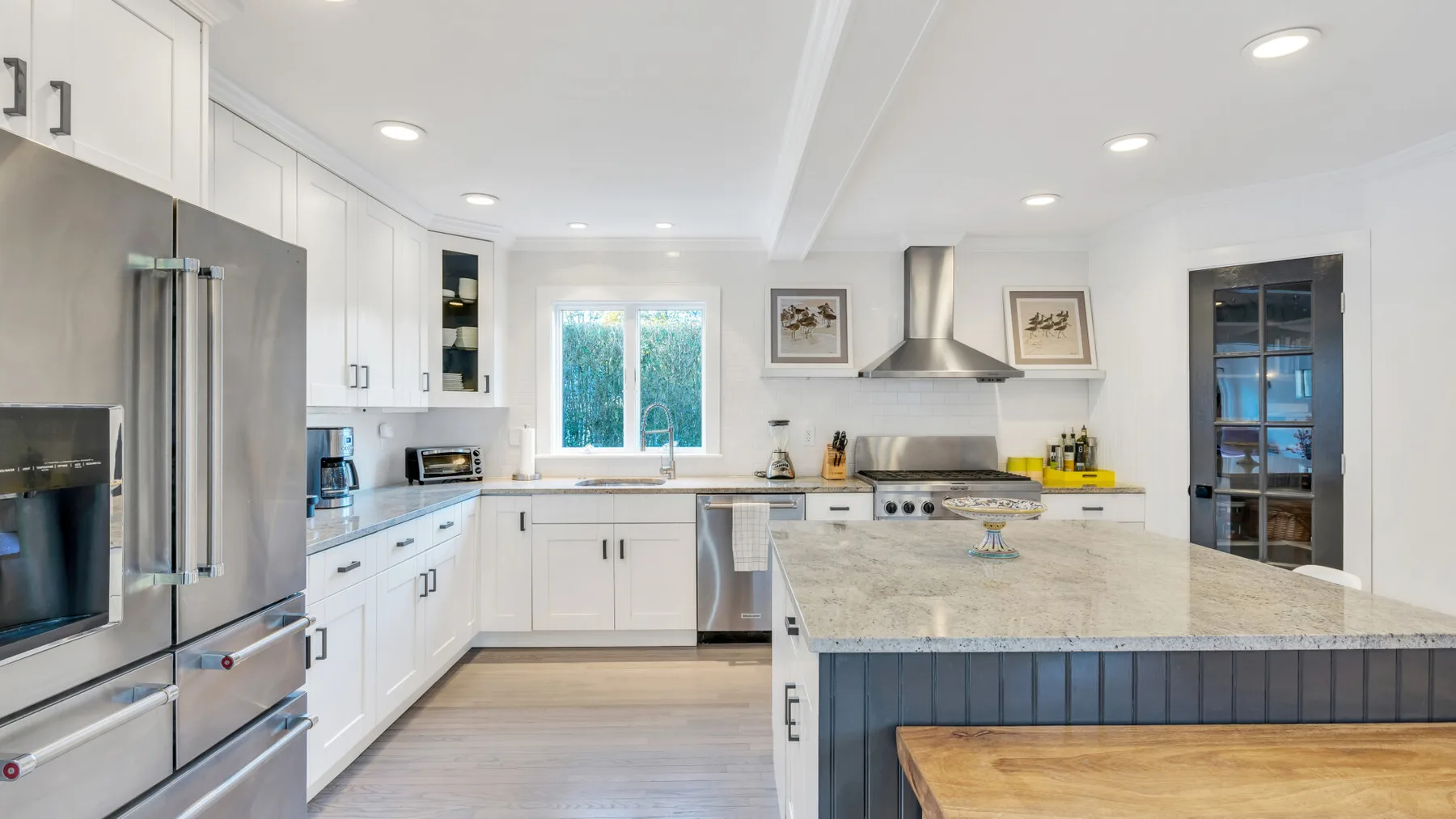 Una cocina luminosa con gabinetes blancos, electrodomésticos de acero inoxidable y una isla grande.