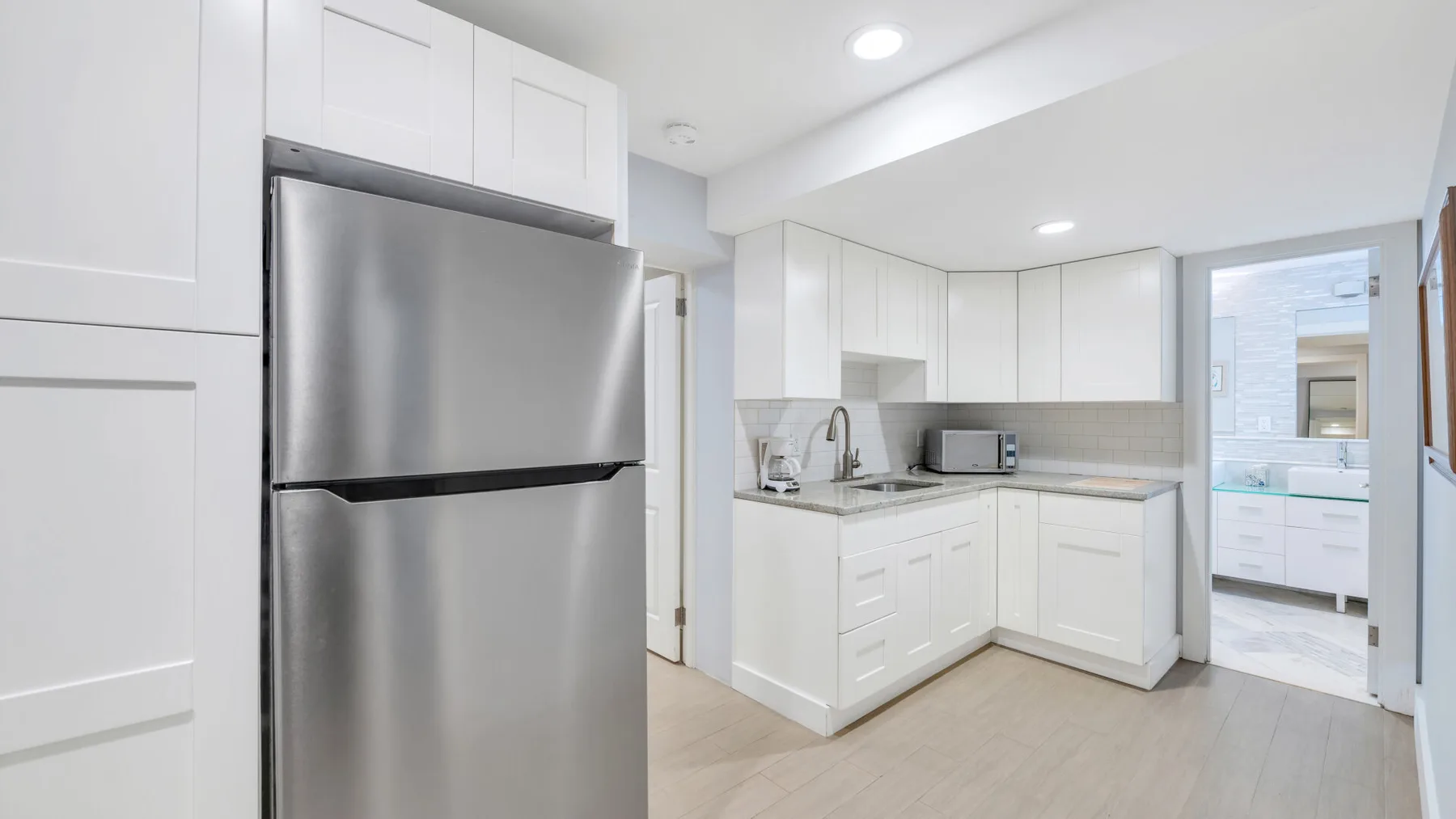 Una cocina luminosa con gabinetes blancos y electrodomésticos de acero inoxidable.