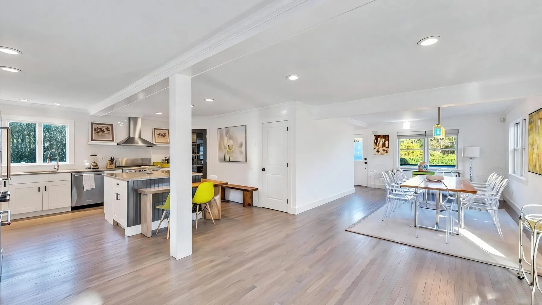 Una cocina y comedor de planta abierta con una mesa junto a grandes ventanas.