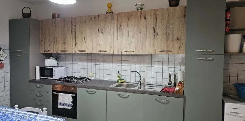 A kitchen with wood-patterned upper cabinets, a tiled backsplash, and a countertop.