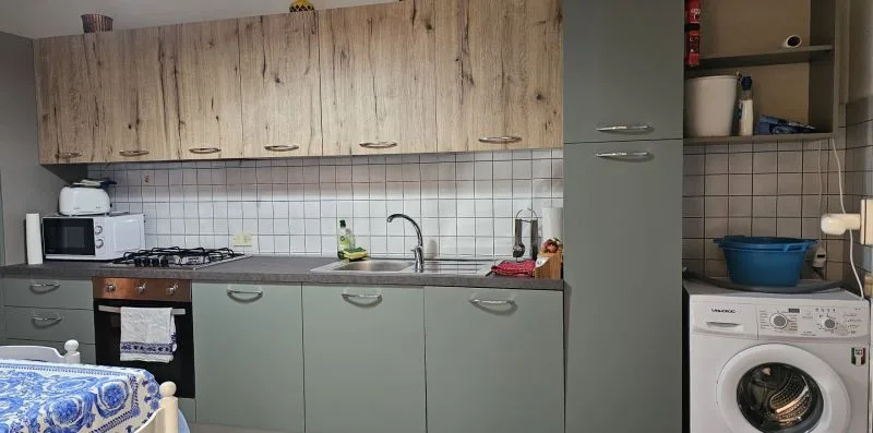 Una cocina con armarios, encimera, placa de cocina y lavadora.