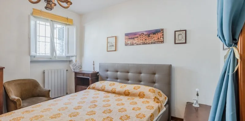 A bedroom with a patterned bedspread, upholstered headboard, and a window.