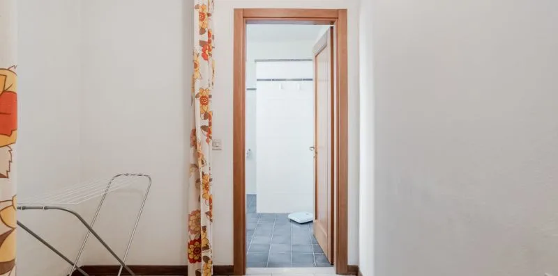A hallway opens into a tiled bathroom, with a patterned curtain beside the doorway.