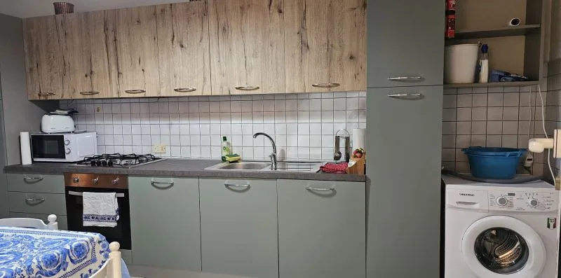 Una cocina con armarios, una encimera y una lavadora.