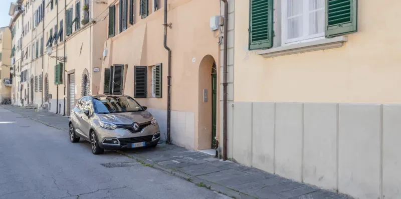 A quiet street lined with pale buildings and a parked car.