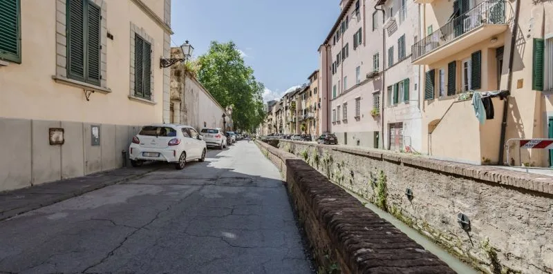 A narrow residential street runs beside a low stone-lined canal.
