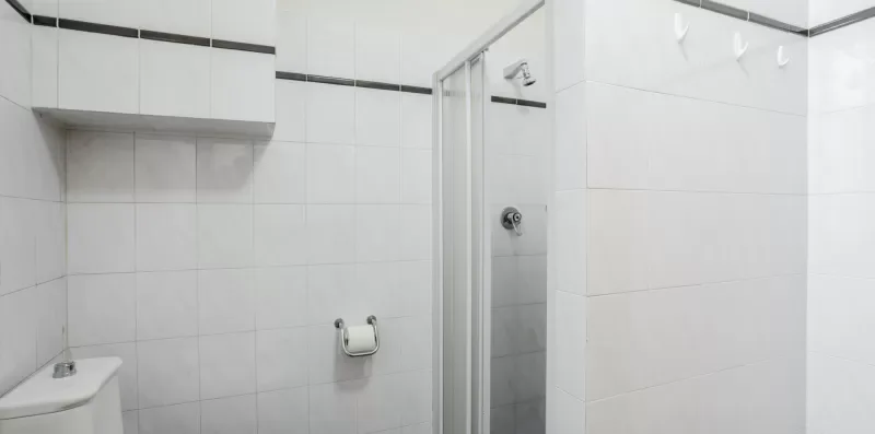 A tiled bathroom with a shower and wall-mounted fixtures.