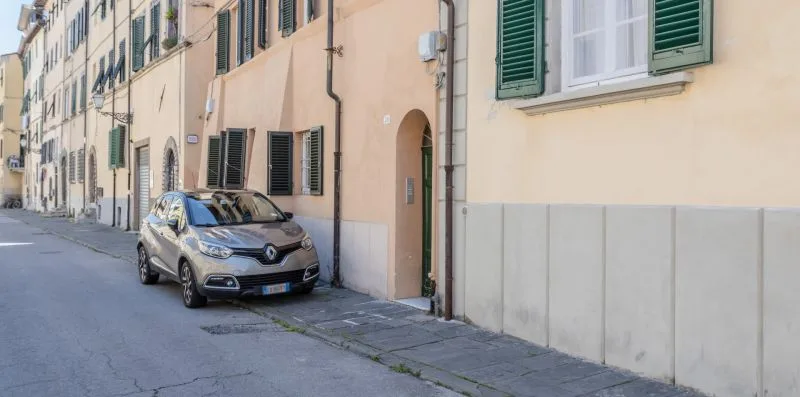 A parked car sits along a narrow street lined with residential buildings.
