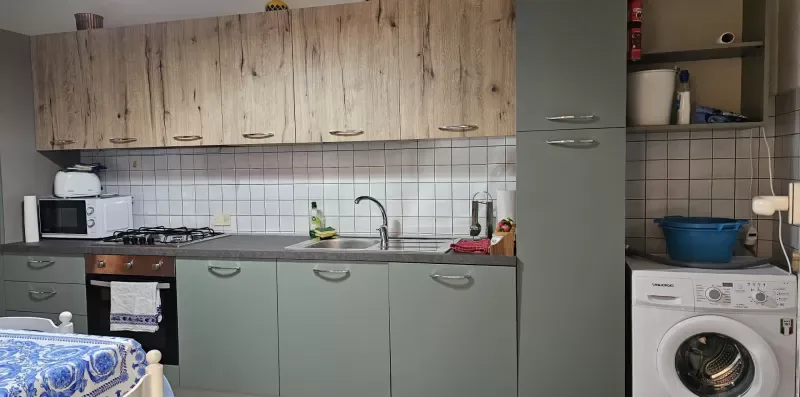 A kitchen with cabinets, a sink, a stove, and a washing machine.