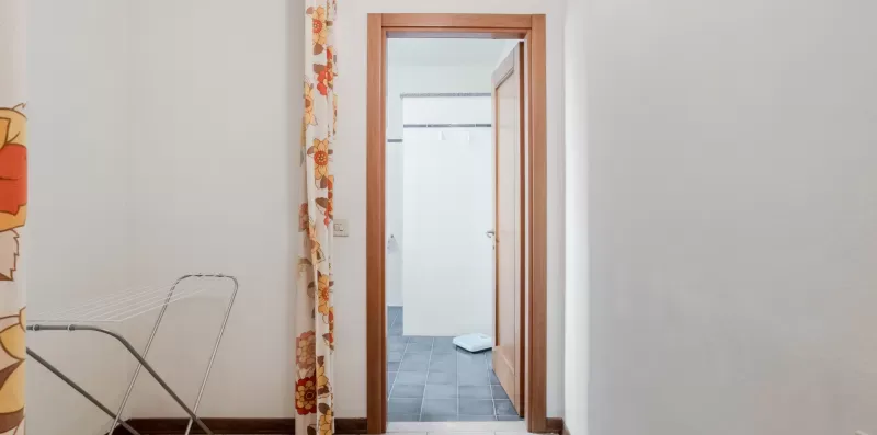 A doorway opens onto a tiled room beside a patterned curtain.