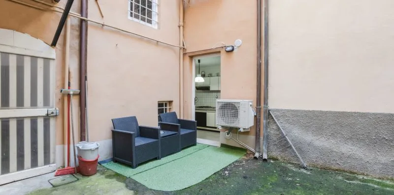 A small outdoor seating area sits beside a glass doorway and wall-mounted air conditioner.