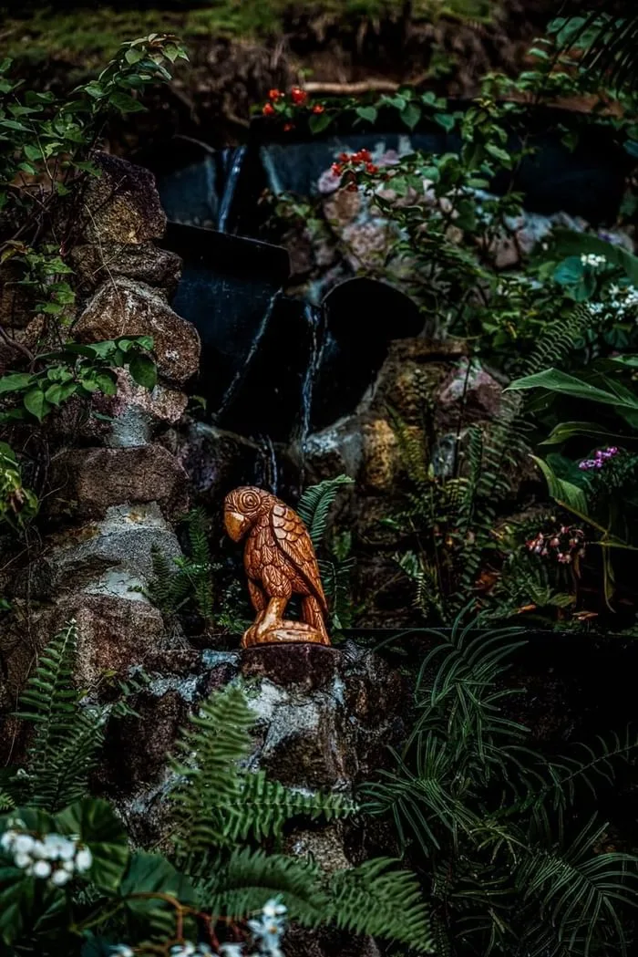 Wooden sculpture beside a small rocky waterfall