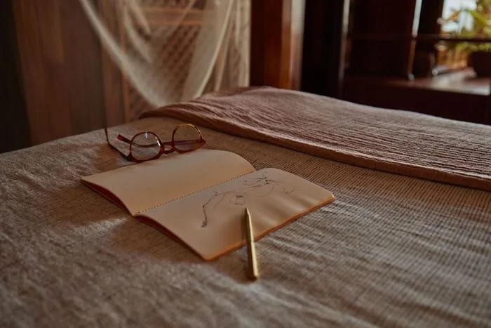 Sketchbook and glasses on a bed