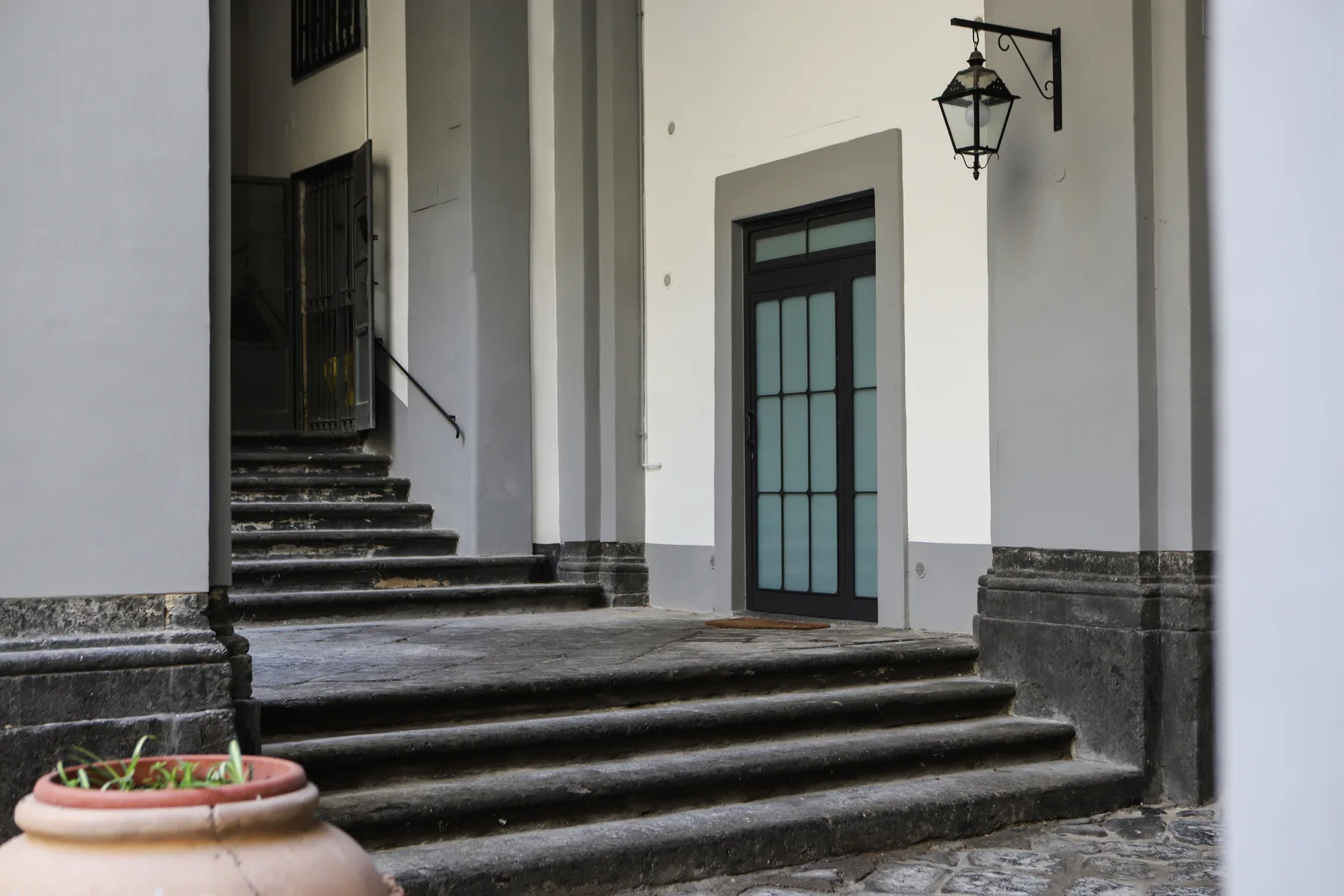 Una entrada exterior con amplios escalones de piedra que conducen a una puerta oscura.