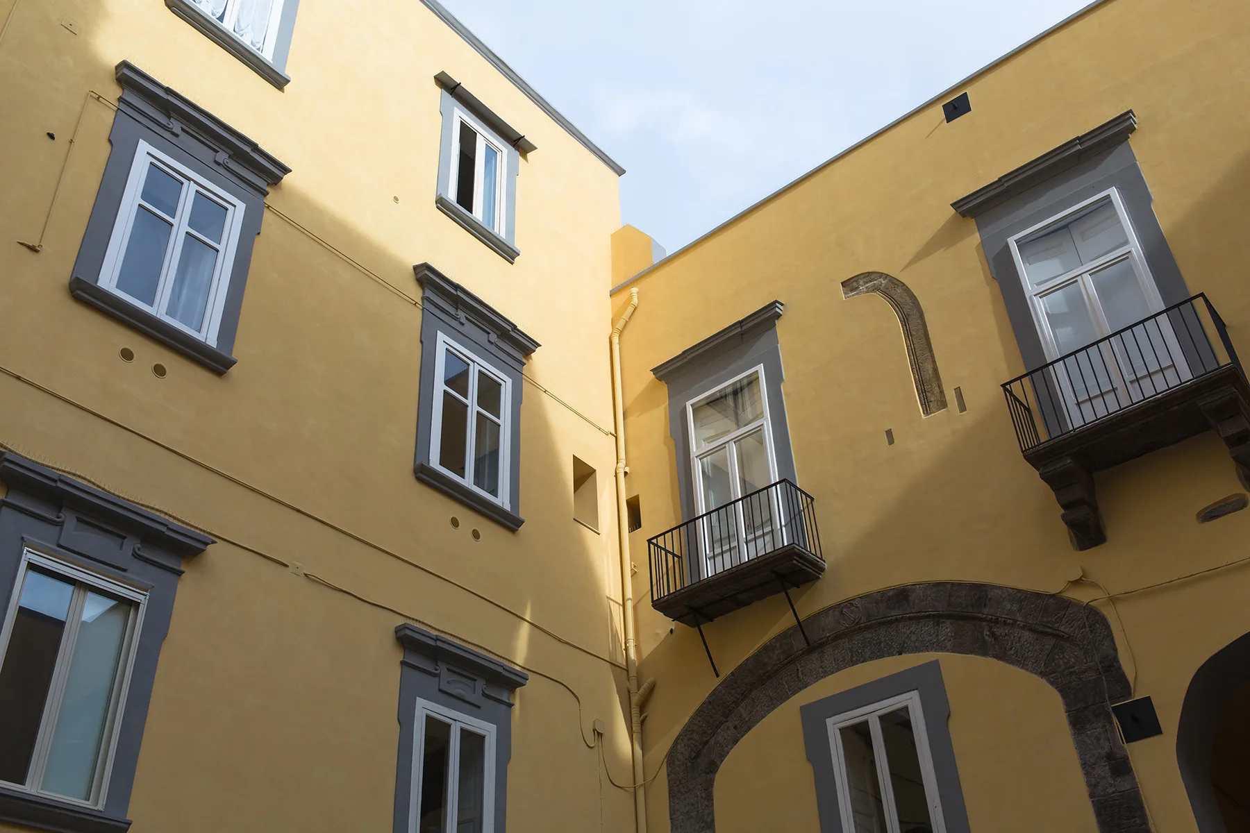 Un patio enmarcado por paredes amarillas con ventanas y pequeños balcones.