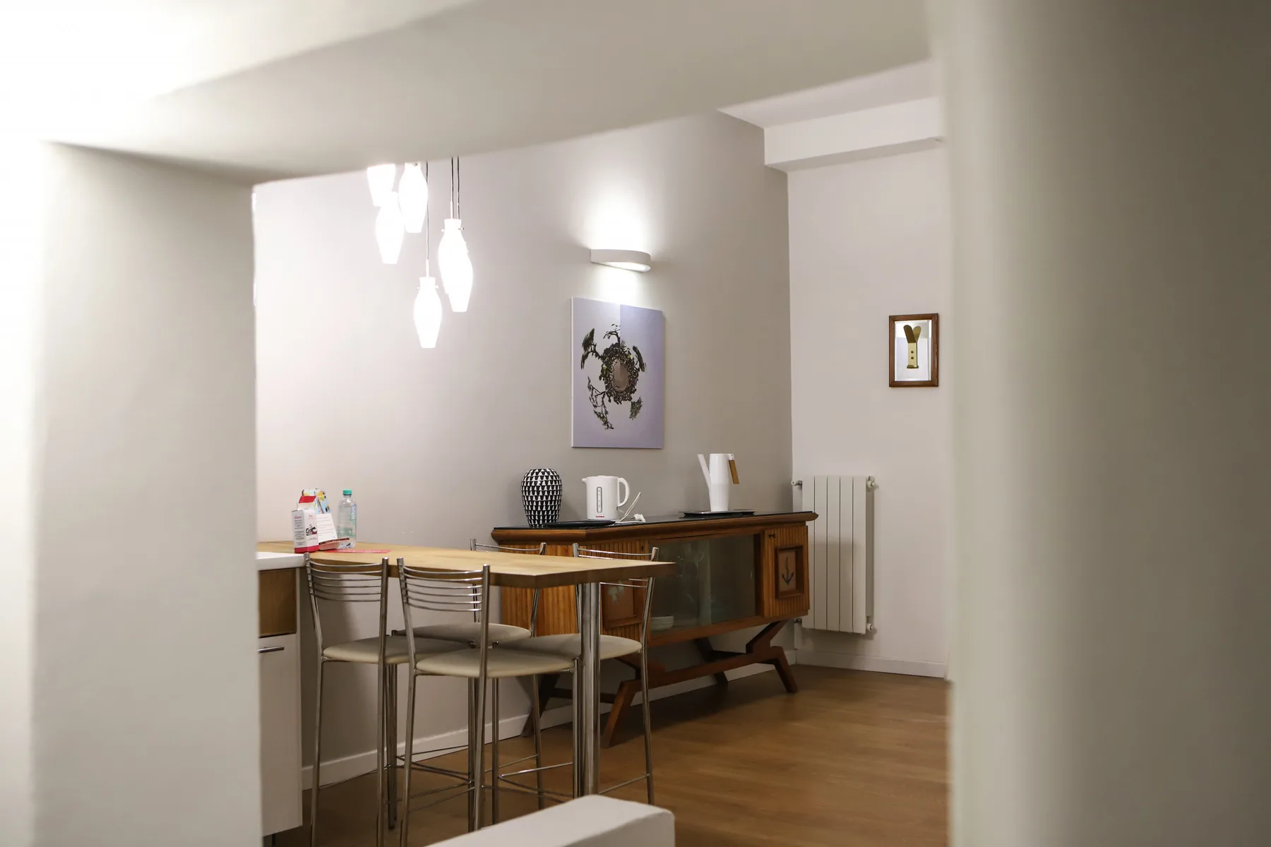 Un comedor con una mesa de madera y sillas bajo luces colgantes.