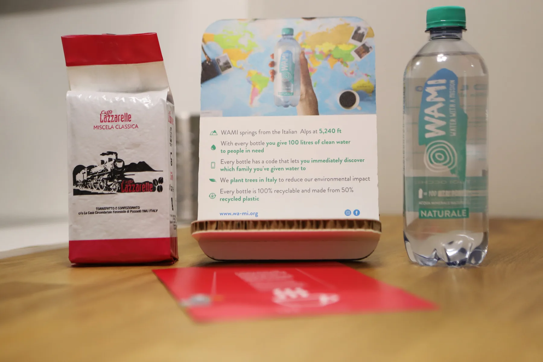 Una mesa muestra un paquete de café, una botella de agua y una tarjeta informativa impresa.