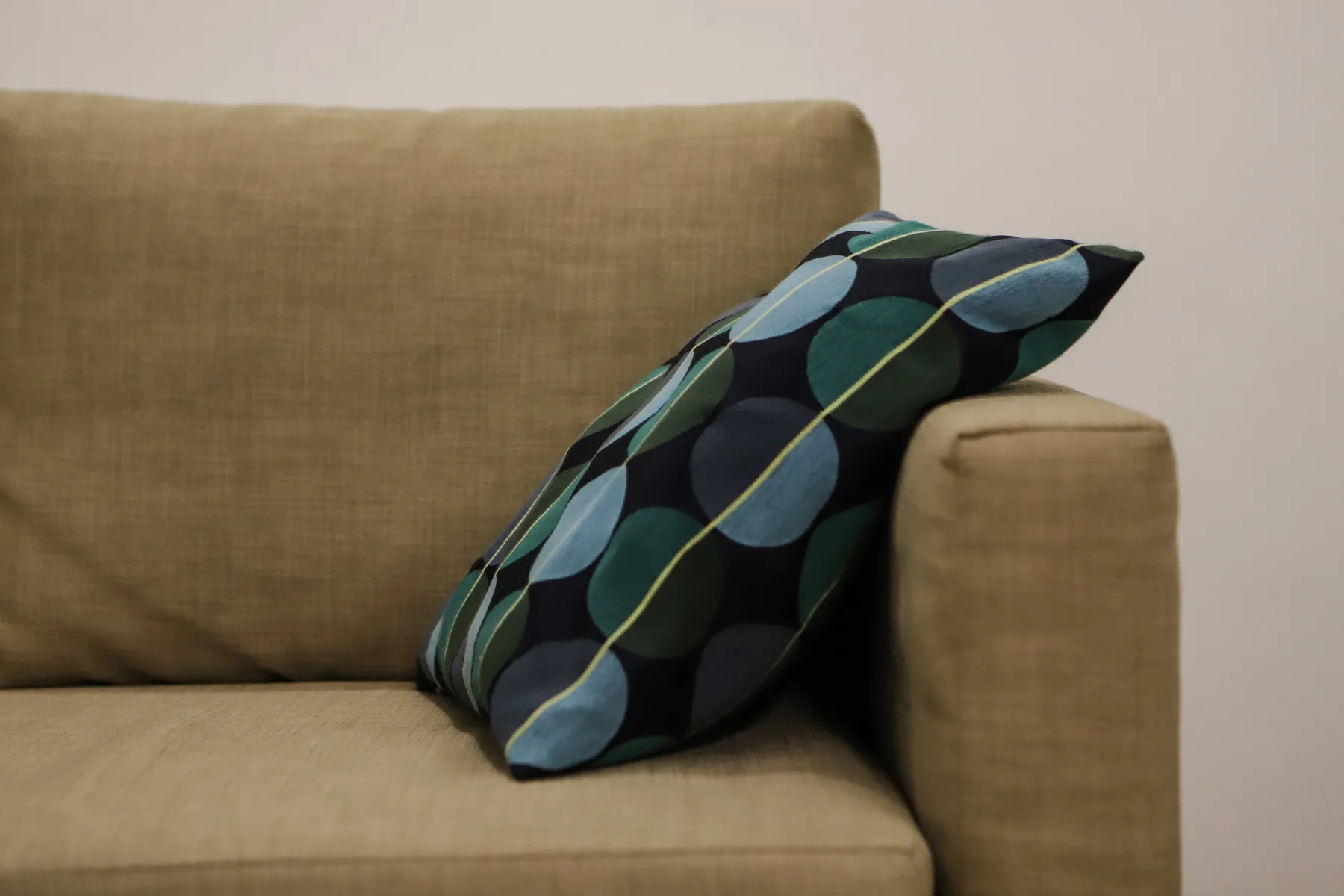 Una zona de estar con un cojín estampado apoyado en el brazo del sofá.
