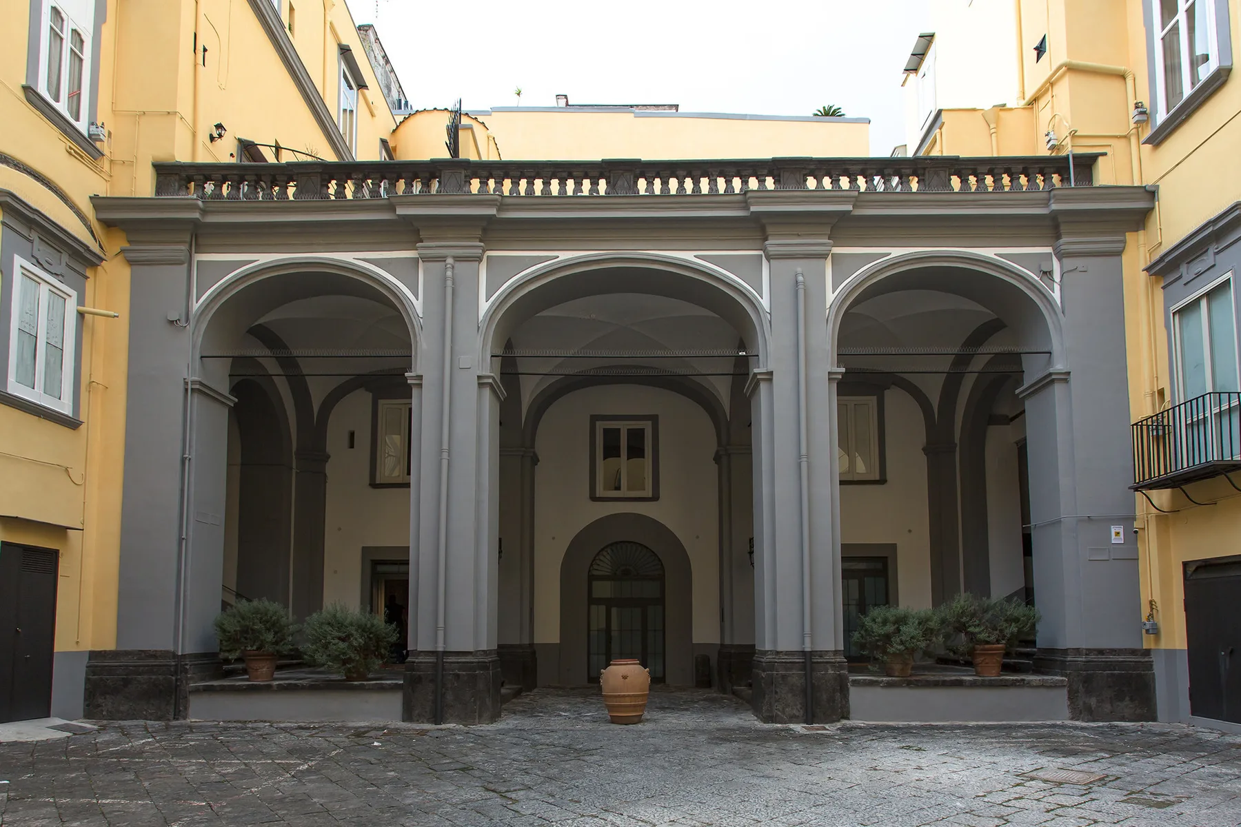Un patio con una galería cubierta y aberturas arqueadas.