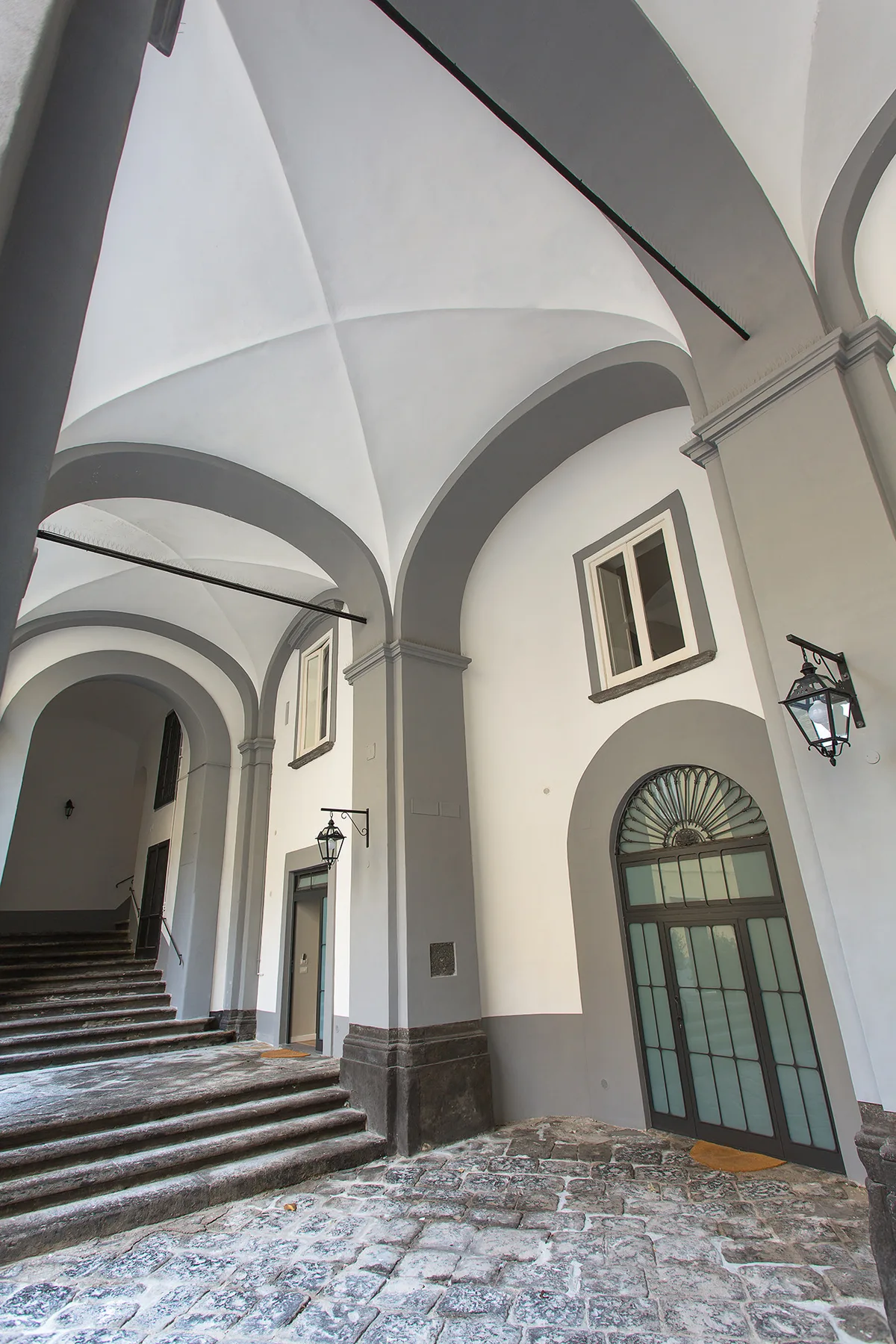 Un pasaje abovedado de piedra con escalones amplios y ventanas altas en arco.
