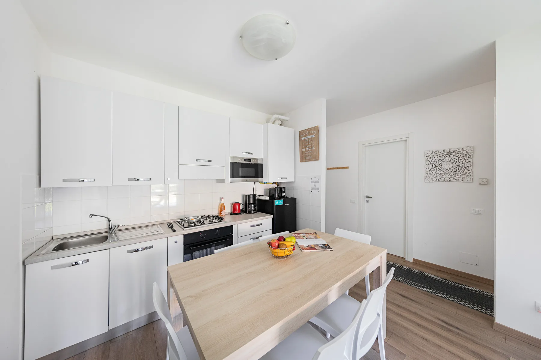 A bright kitchen and dining area with white cabinets and a wooden table.