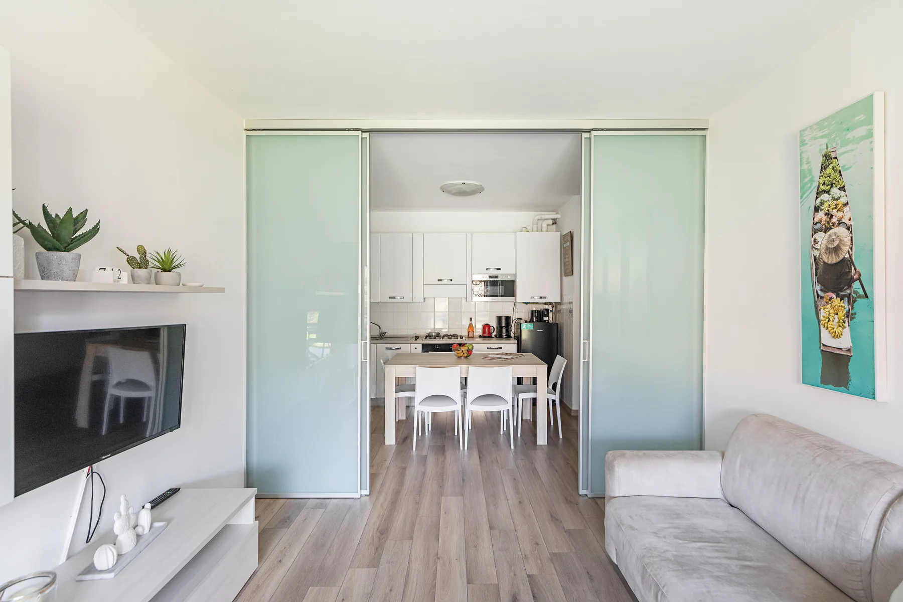 A bright living area opens onto a compact kitchen, with seating and a dining table.
