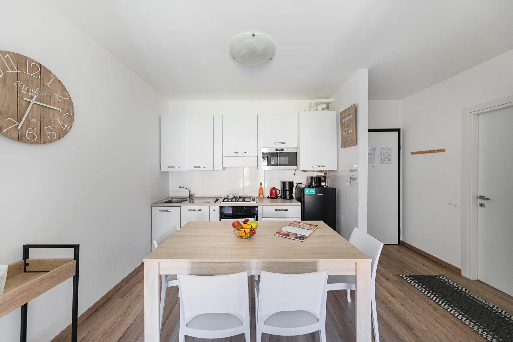 A bright kitchen and dining area with white cabinets and a wooden table.