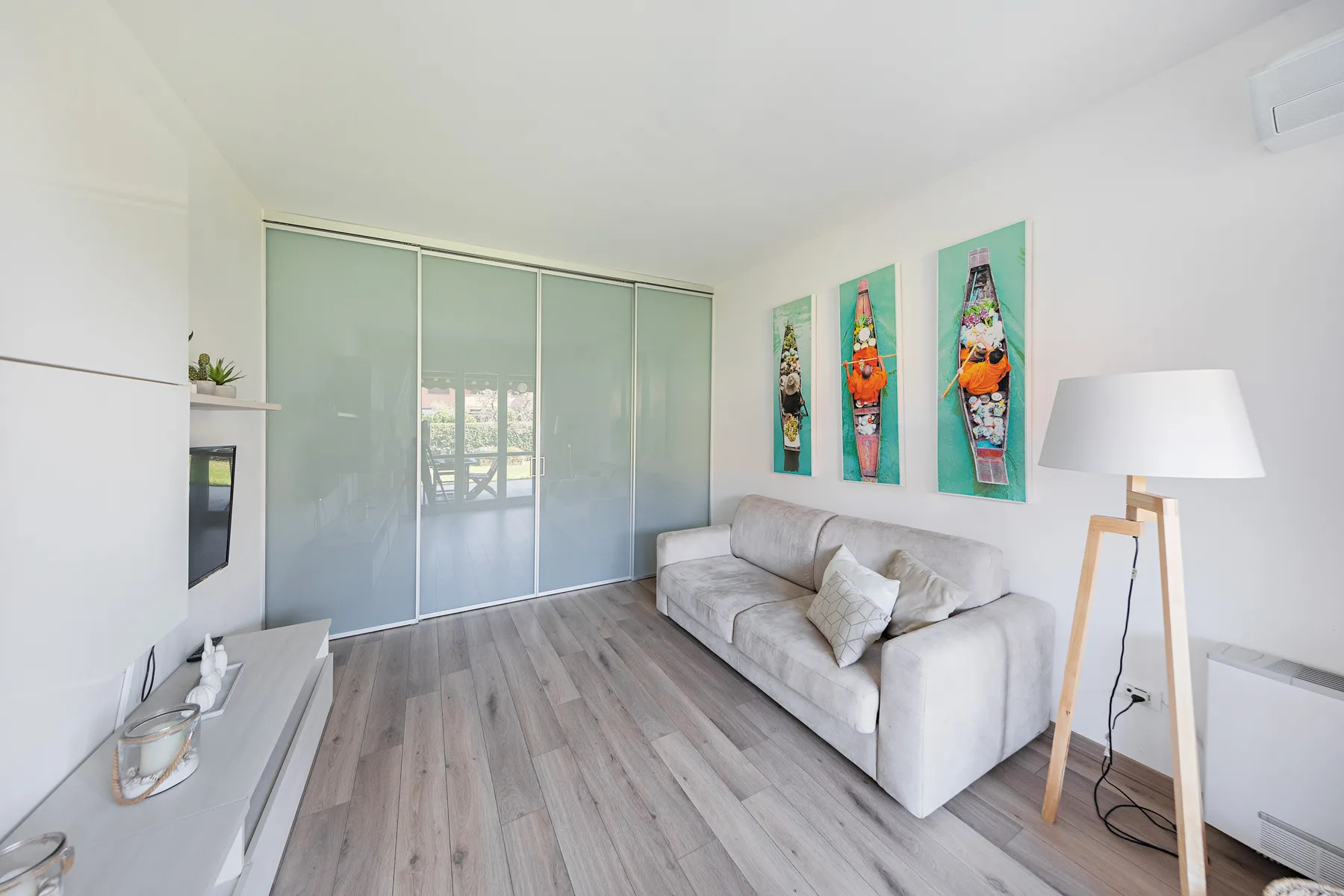 A bright living room with a sofa, sliding glass doors, and colorful wall art.