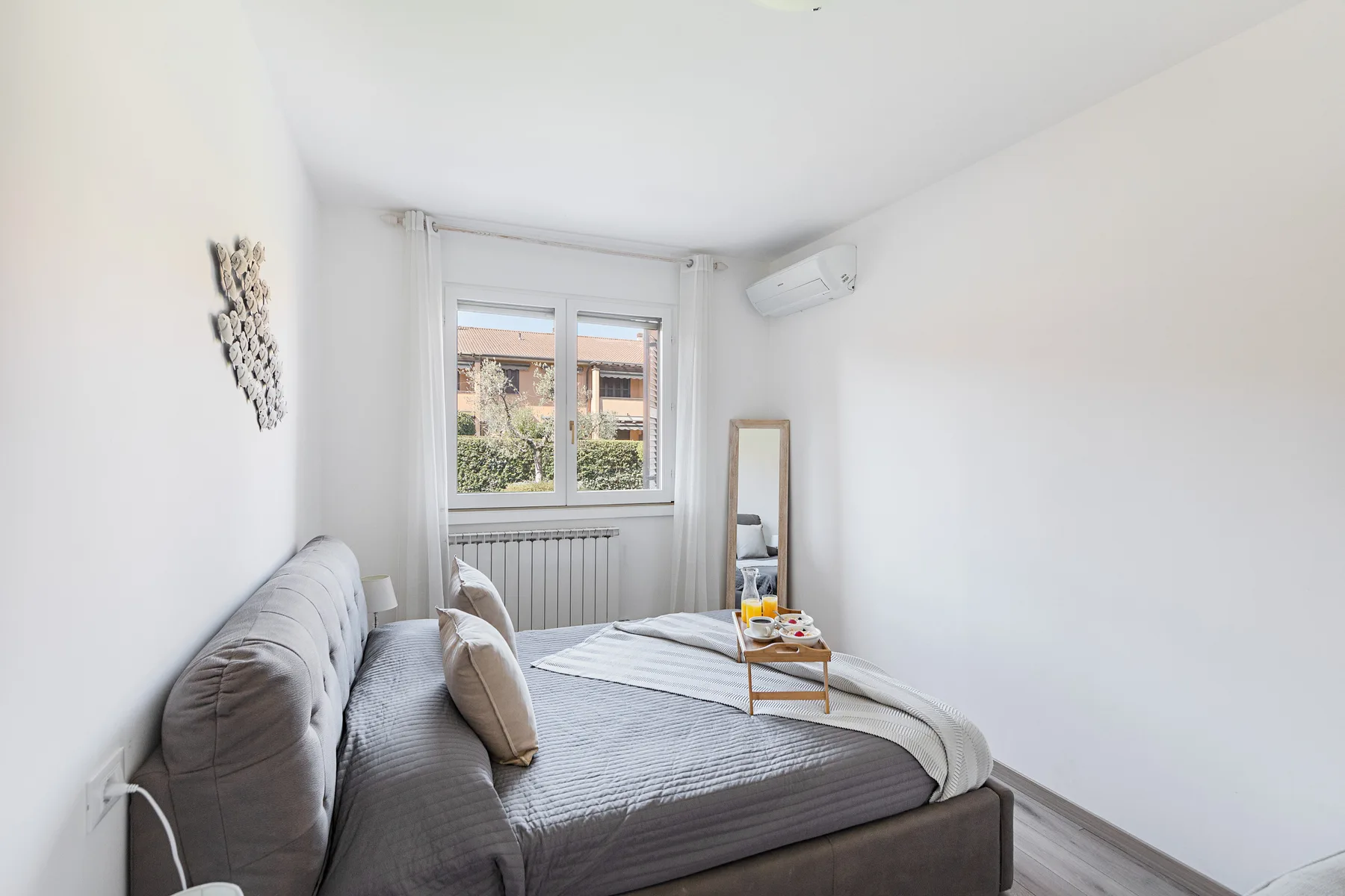 A bright bedroom with a large bed, a window, and a small table.