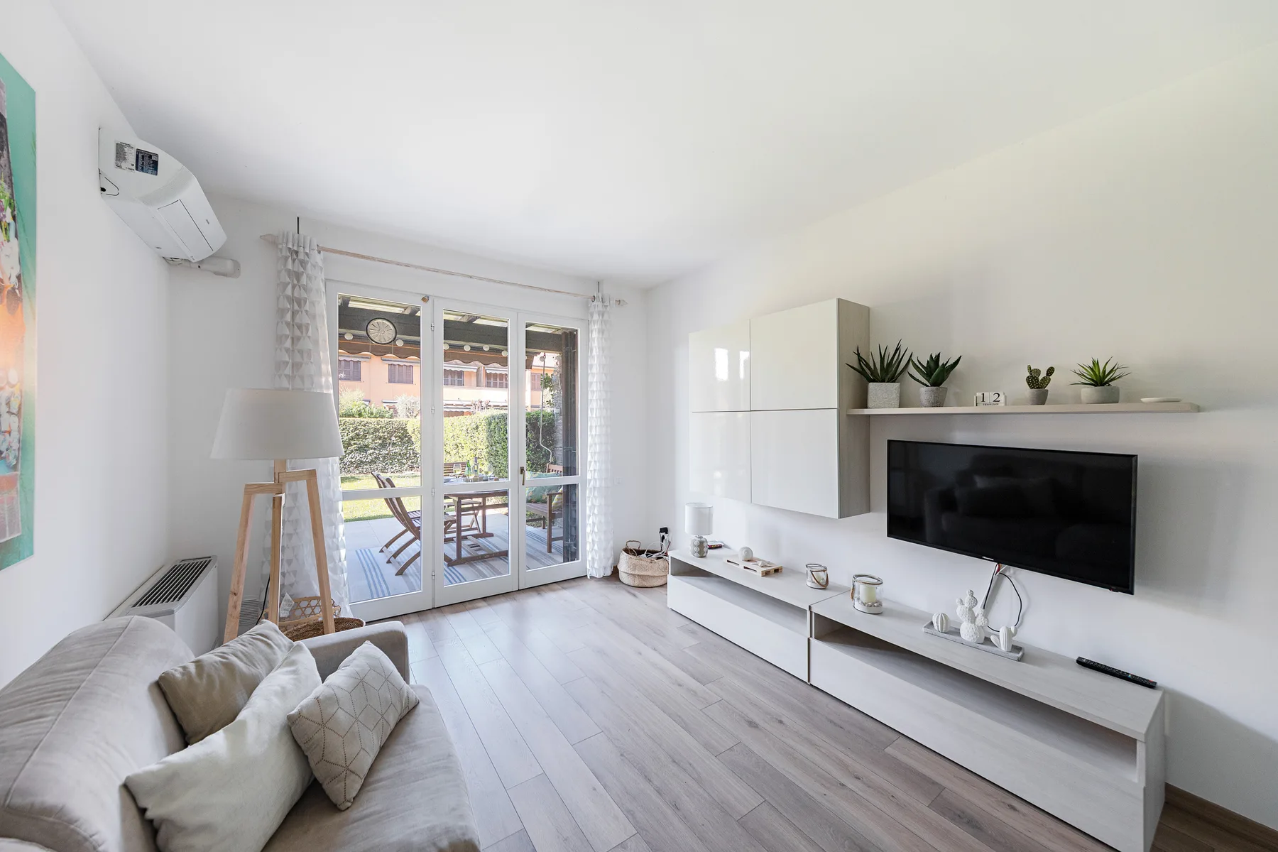 A bright living room with seating, a television, and glass doors opening to a patio.