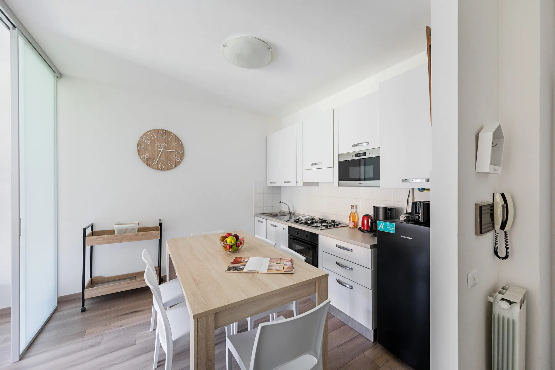 A bright kitchen and dining area with a table beside white cabinets.