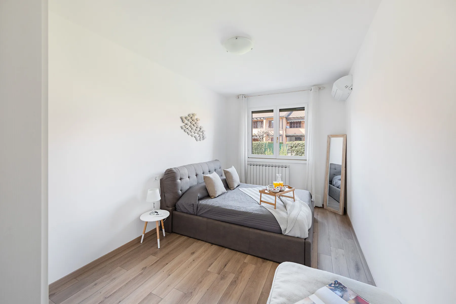 A bright bedroom with a bed, a window, and a small table.