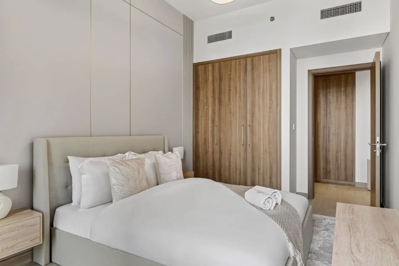 A bedroom with a neatly made bed and wood-paneled closet doors.