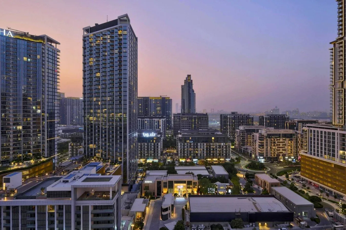 City skyline at dusk with modern high-rise buildings and illuminated streets.