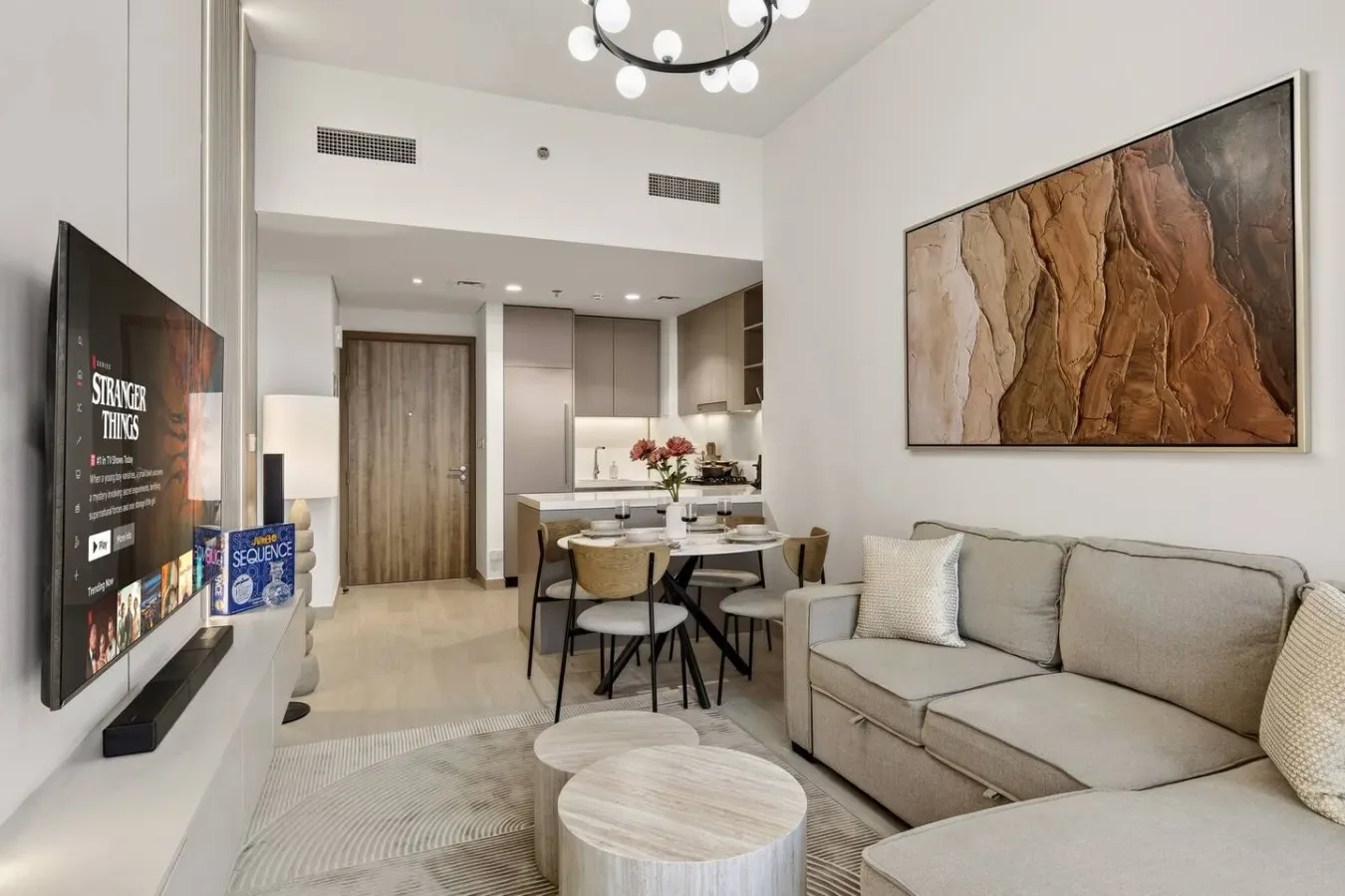 A bright living and dining area with a sofa, table, and wall art.
