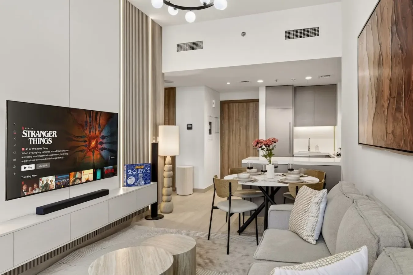 A bright open-plan living and dining area with a television and table.