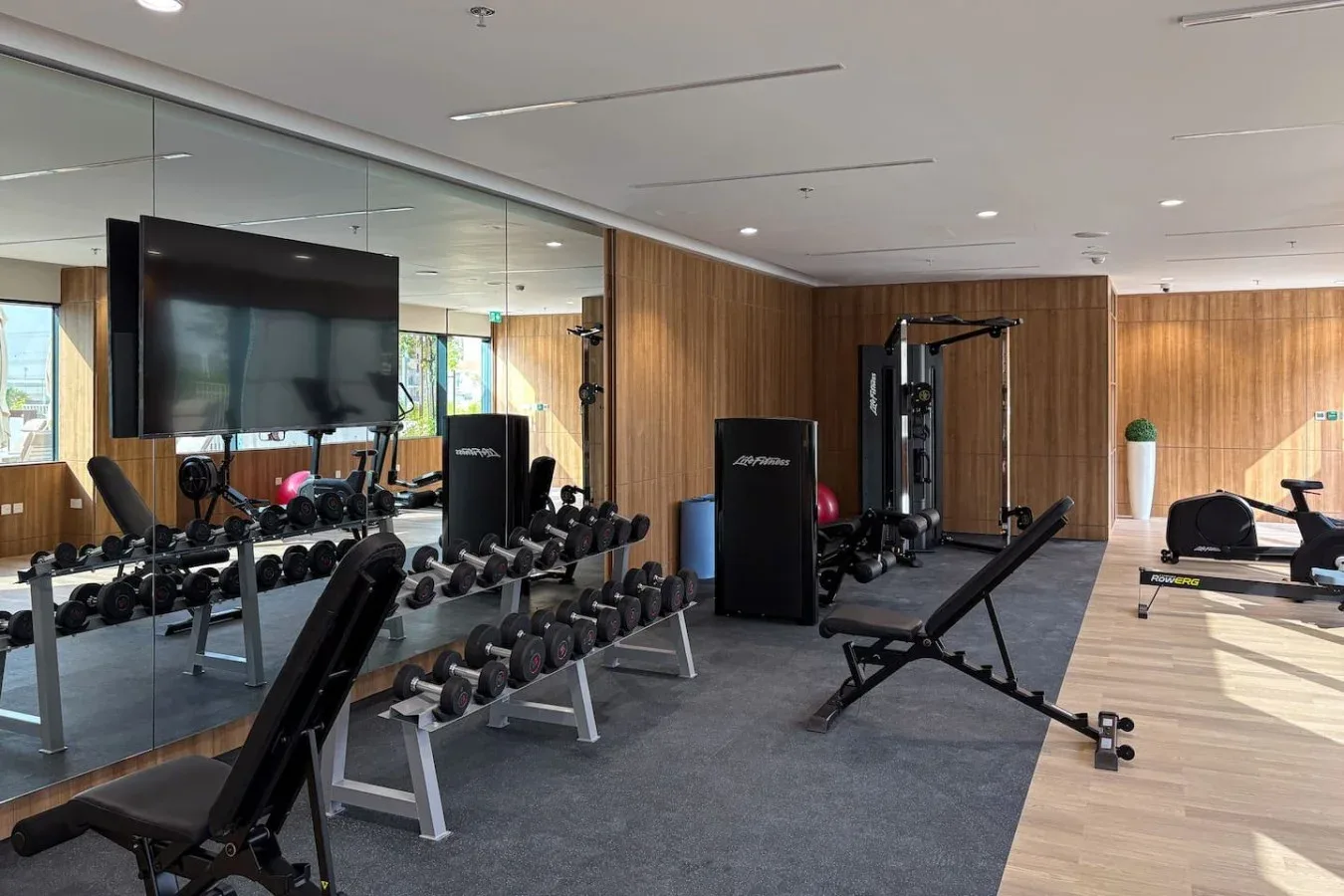 A fitness room with weight racks, exercise machines, and benches.