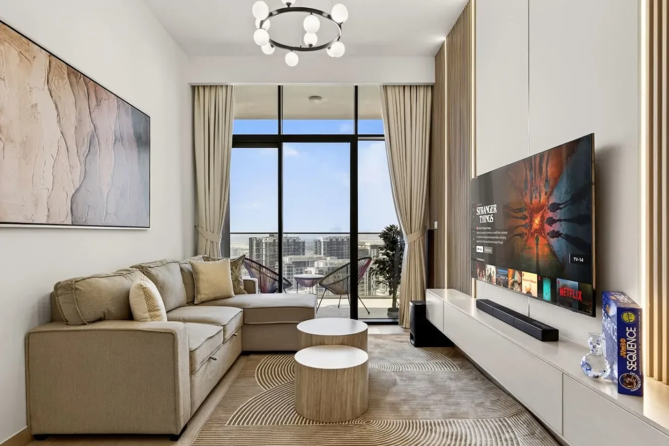 Una sala de estar con asientos, un televisor y grandes ventanas con vistas a la ciudad.